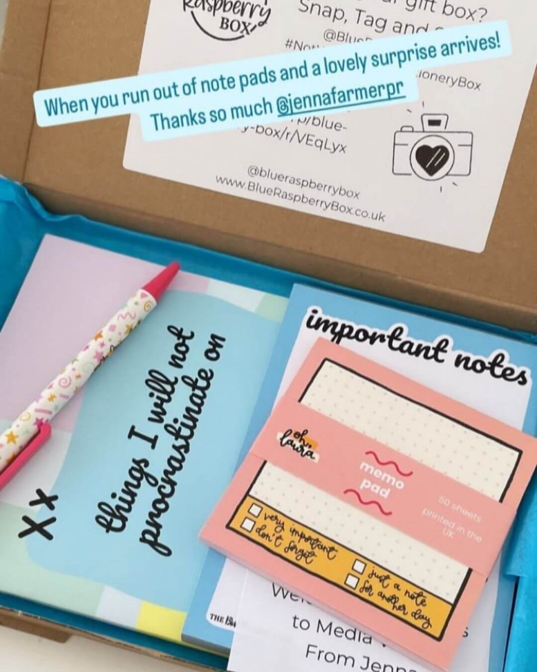 Open Blue Raspberry gift box with stationery items and a promotional card.