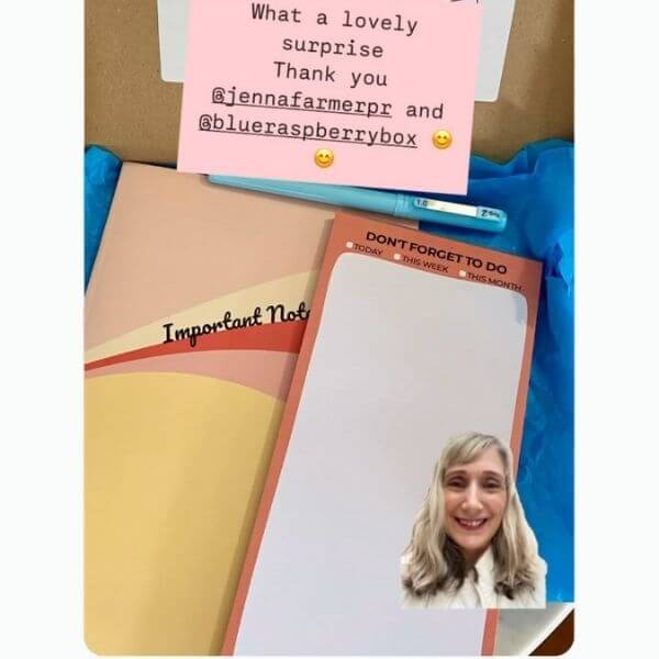 Notebook, notepad and pen with a photo of a woman gif and a pink text block inside an open gift box with blue tissue paper